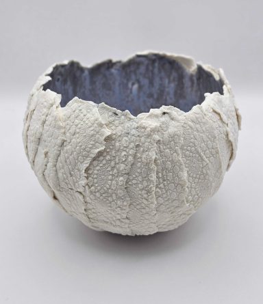 Porcelain bowl with white, lace-patterned exterior and blue glaze inside.